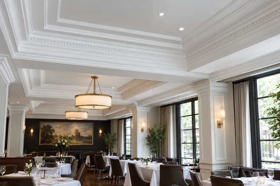 Concept image of EPS foam crown moldings and cornices painted white on a restaurant dining room ceiling.