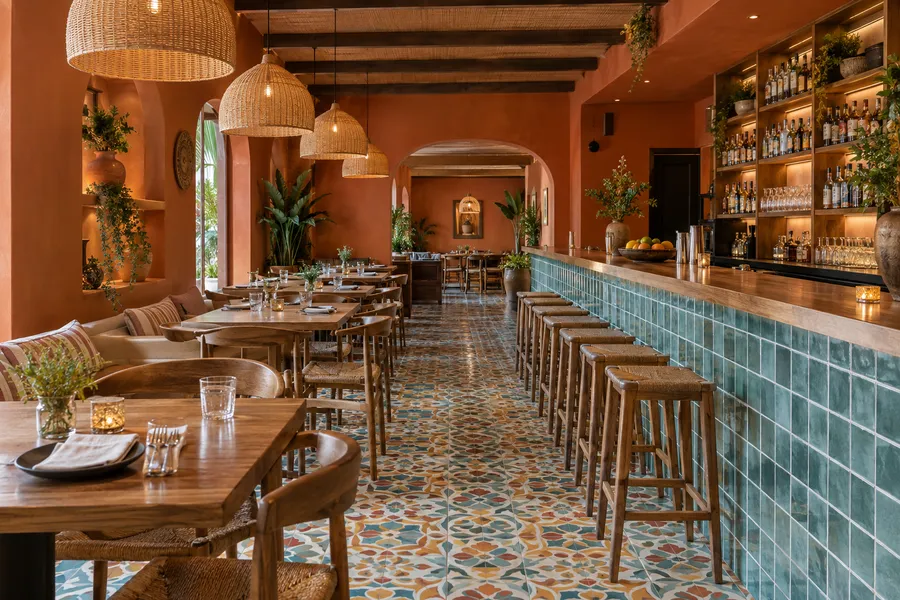 Concept image of a Latin tapas restaurant with cement tile floors, a long tiled bar, rattan pendants and terracotta walls.