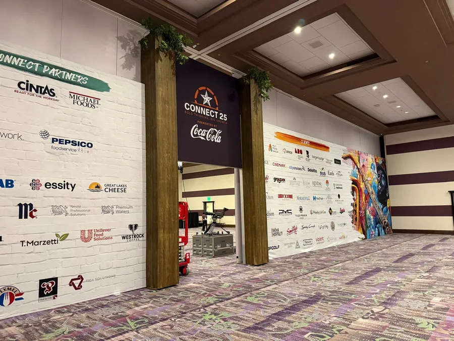 A Connect 25 partner wall with sponsor logos, timber portal columns and a Coca-Cola banner.