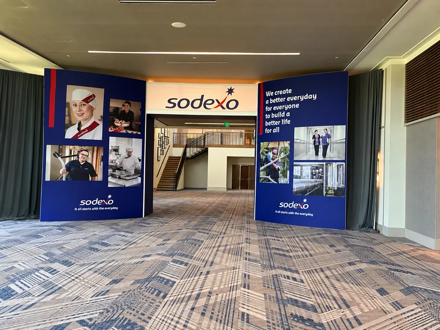 A Sodexo branded entry portal with navy graphic towers framing the entrance to a conference hall.