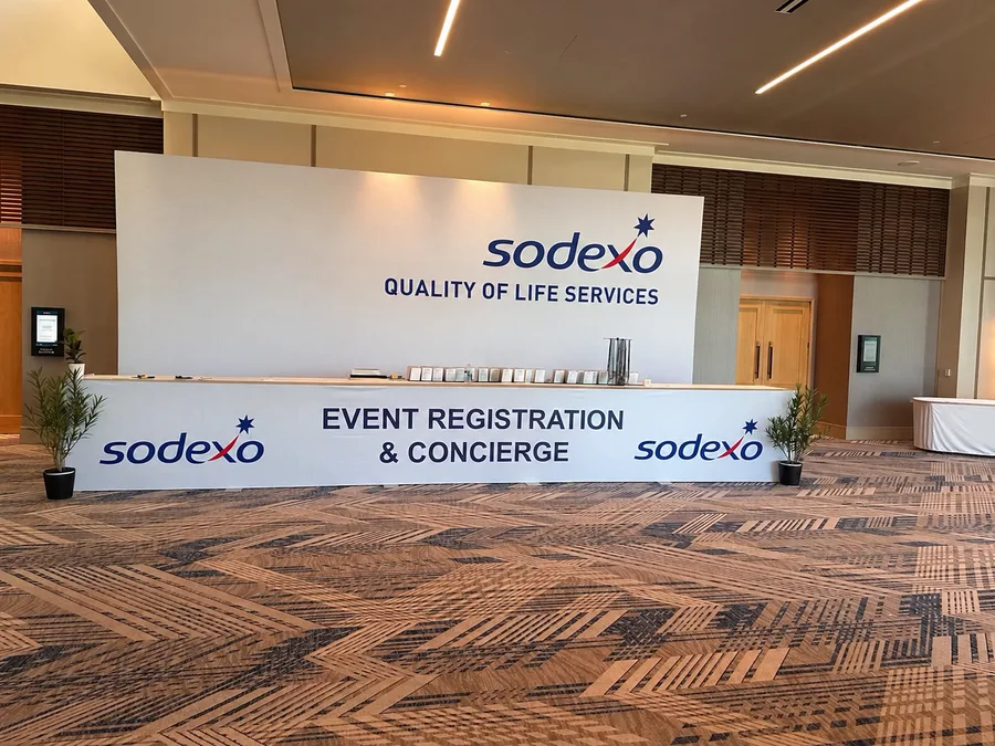 A Sodexo Quality of Life Services event registration and concierge desk with a large branded backdrop.