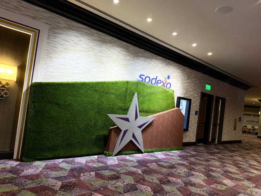 A Sodexo turf wall with a large dimensional star and wood-look panel in a conference corridor.